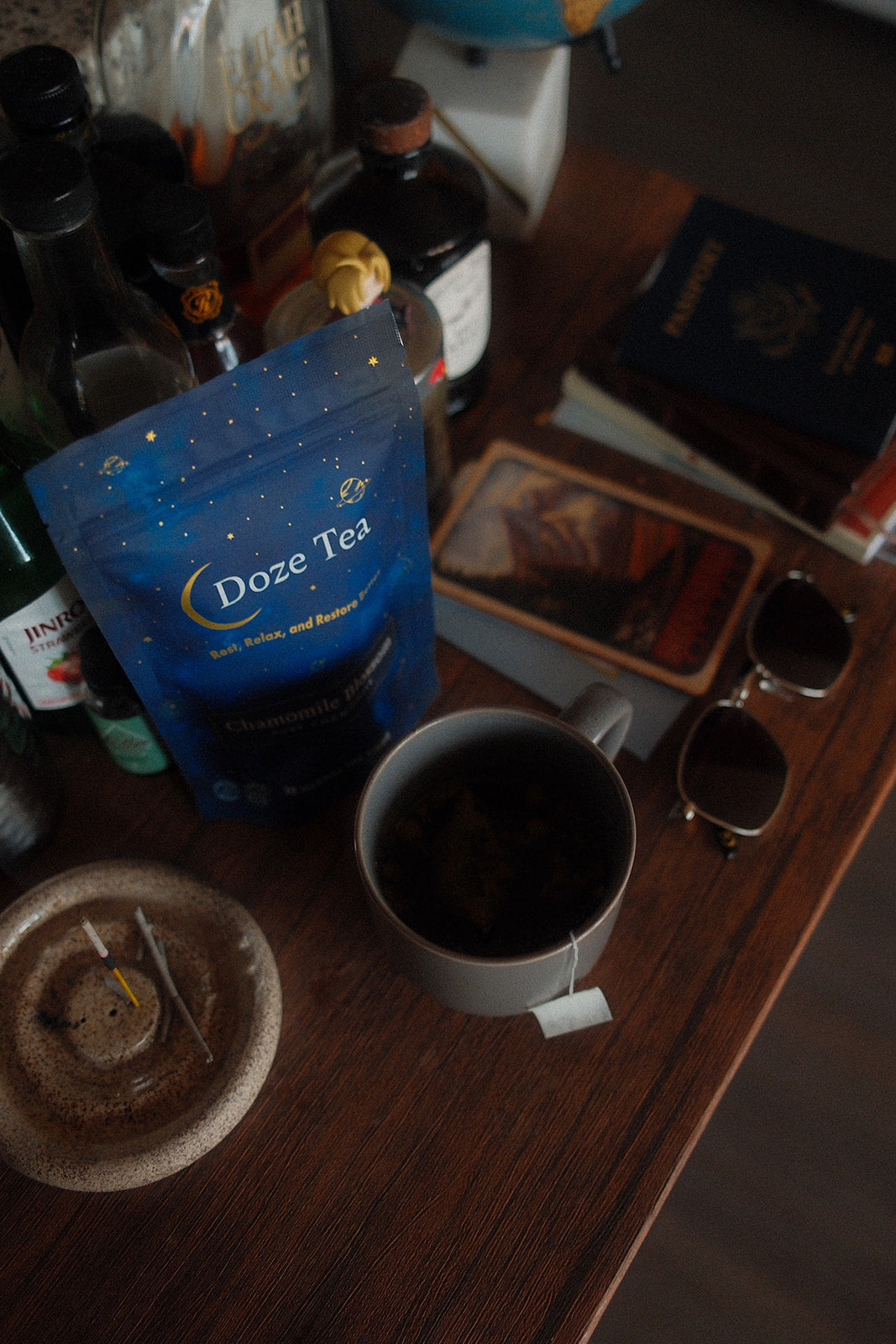 Cup of Doze Tea and calming bedside items in a soft, cozy environment