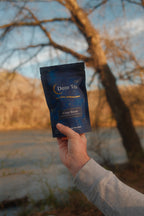 Person holding a Doze Tea bag in a cozy setting for a relaxing nighttime routine